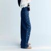 A stylish wide-leg denim pant featuring delicate hand-applied crystal details on the front for a subtle touch of sparkle. Designed with patch pockets at the back and finished with TNS embroidery on the waistband, it combines casual comfort with refined, unique details.  Model: Height 176 cm. Is wearing size S  Made in India  Color Collection: Blue Denim  100% Cotton